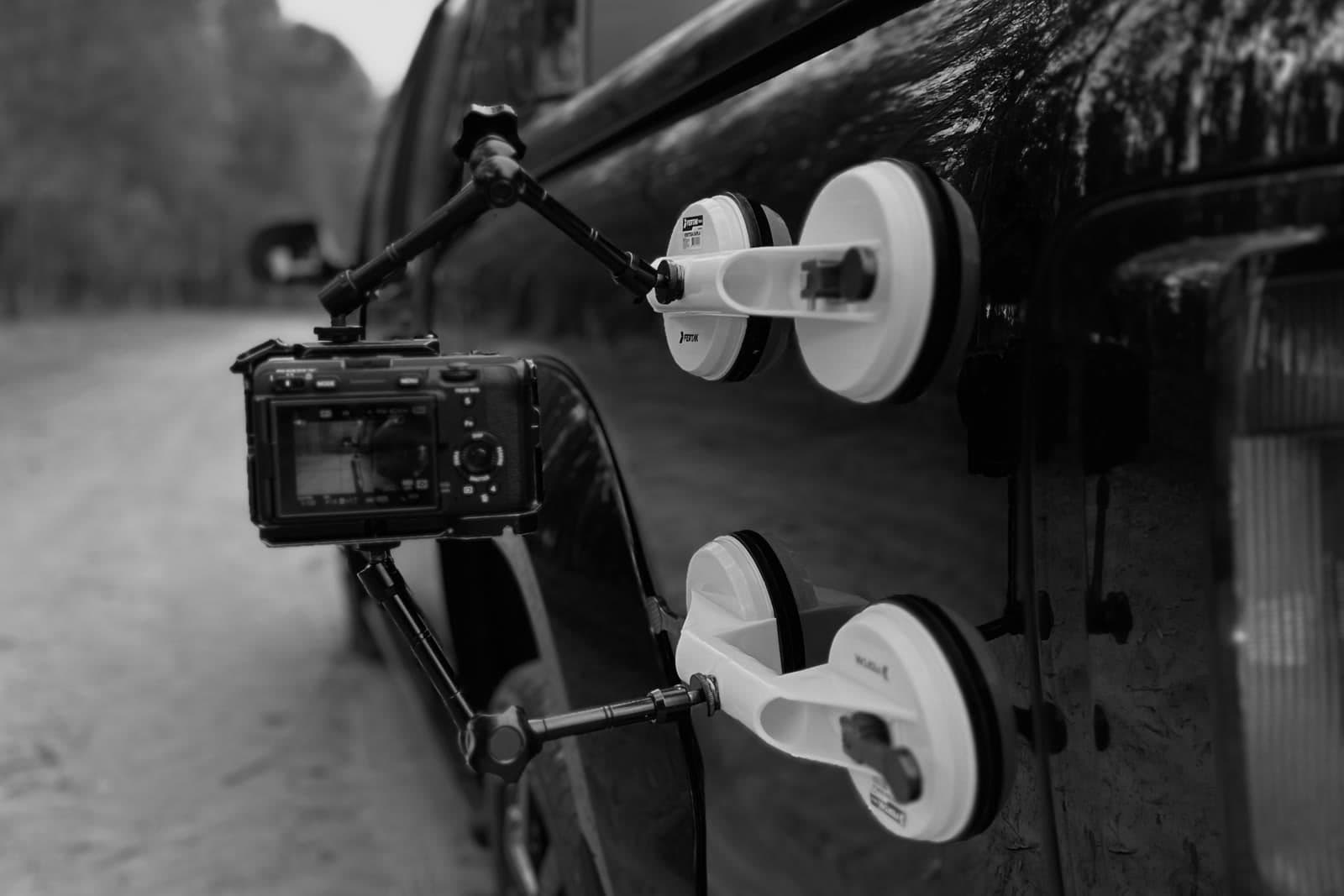 Câmera presa com ventosas na lateral de uma picape, em bastidor de filmagem