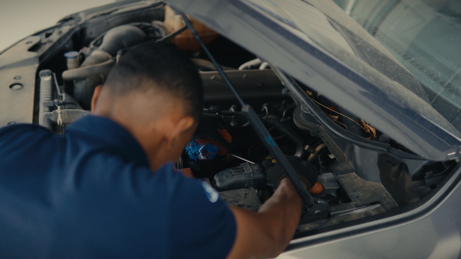 Mãos no motor de um veículo em manutenção, do filme Petrolina para a Ford Buriti.